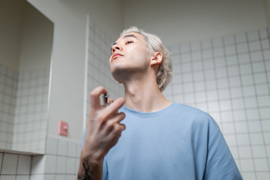 A stylish young man applying perfume in a contemporary bathroom setting, embracing a metrosexual lifestyle.