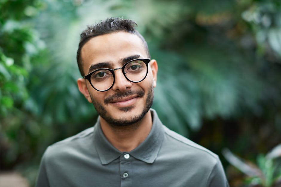 Portrait of a cheerful man outdoors wearing glasses and a polo shirt.