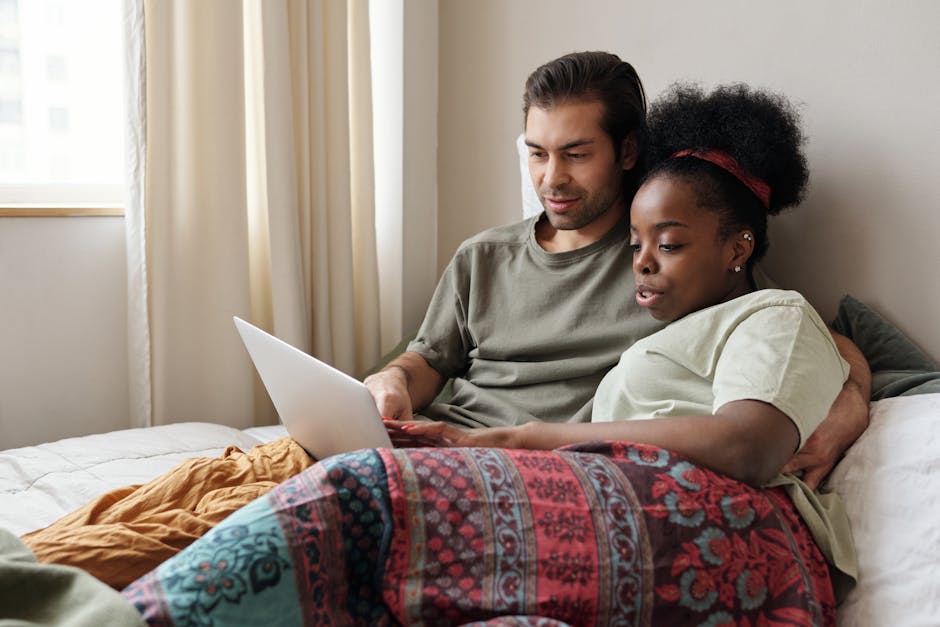 Cozy multiracial couple enjoying quality time at home with a laptop, emphasizing love and connection.