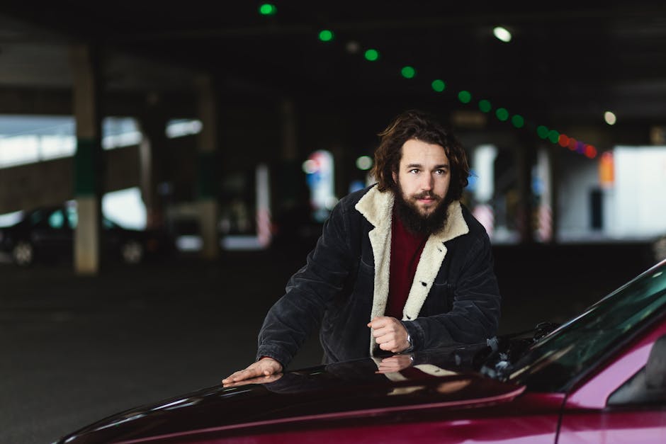 Bearded man in a coat leans on a car in an urban parking area, Гродно, Belarus.