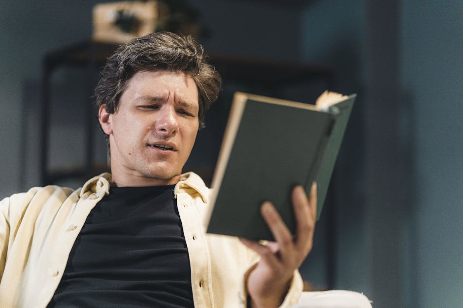 Man deeply engaged in reading a book, expressing curiosity or confusion.