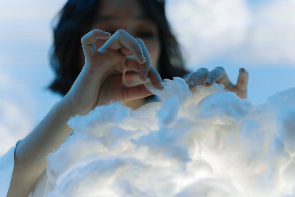 Close-up of a woman’s hands interacting with soft, fluffy cotton in an artistic setting.