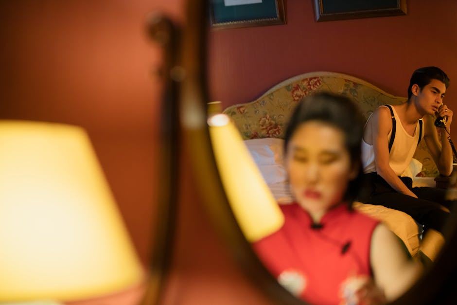 A couple in a bedroom communicating through a phone, with a reflective and intimate ambiance.