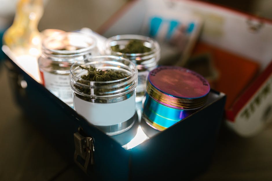 A storage box containing glass jars of cannabis with a vibrant lid under soft lighting.
