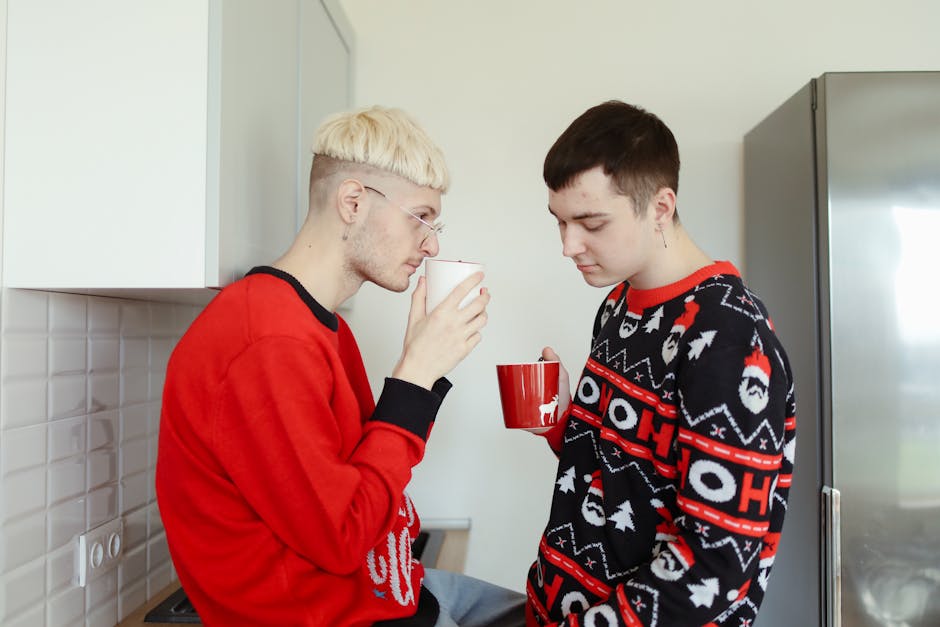 Two men enjoying a warm drink in festive sweaters, conveying love and togetherness.