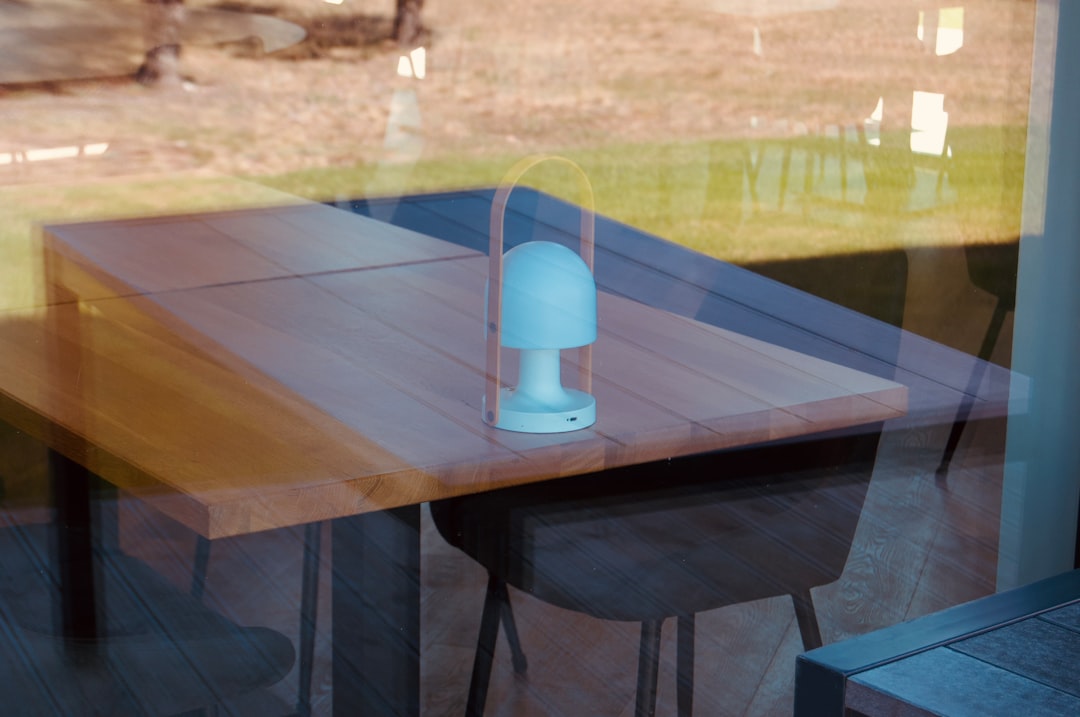 A lamp sits on a table by a window.