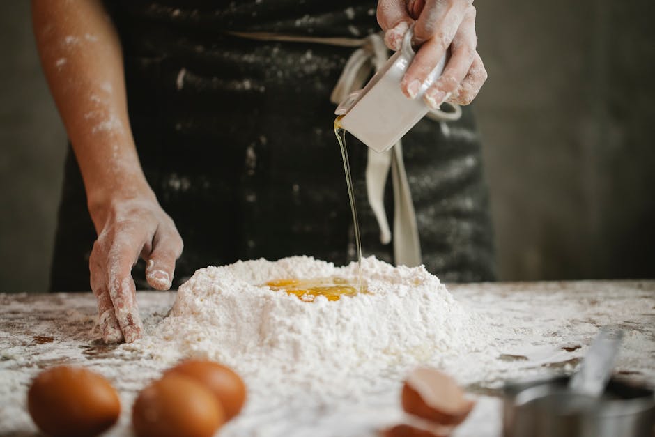 Chef pouring oil into flour and egg mix for homemade pasta.