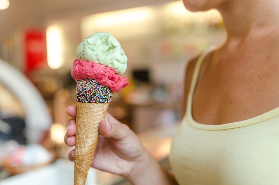A close-up of a woman holding a delicious ice cream cone with sprinkles indoors.