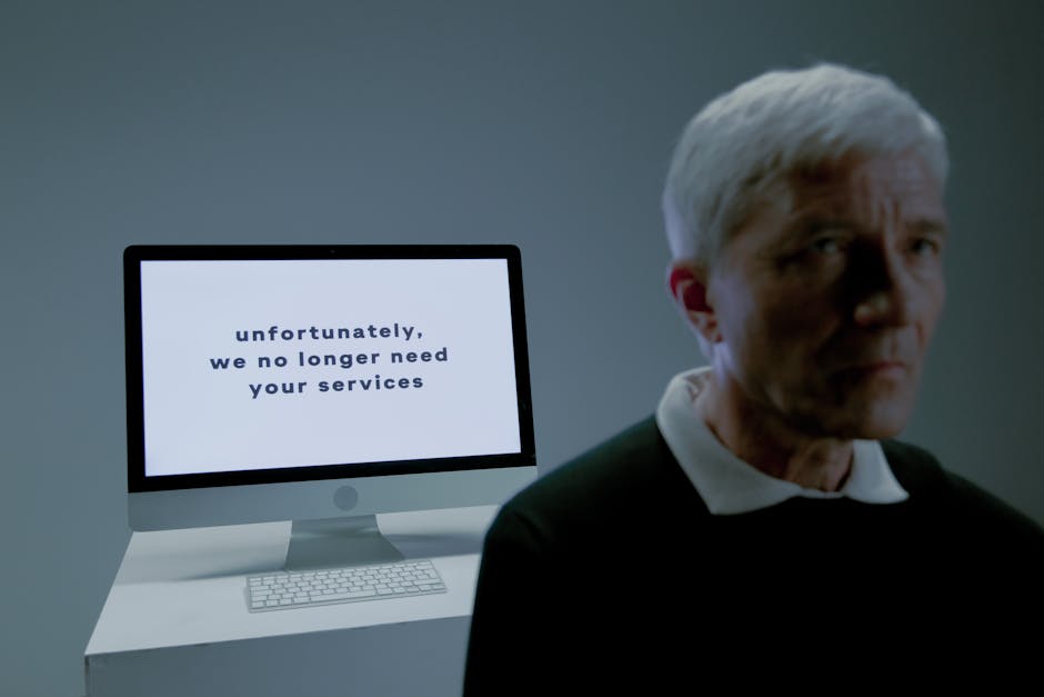 Senior man looks away from an unemployment notice on a computer screen indoors.