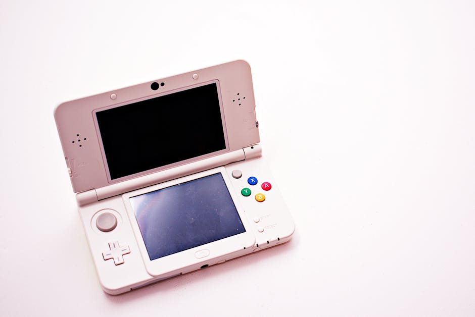 A clean shot of a white portable gaming console with two screens.