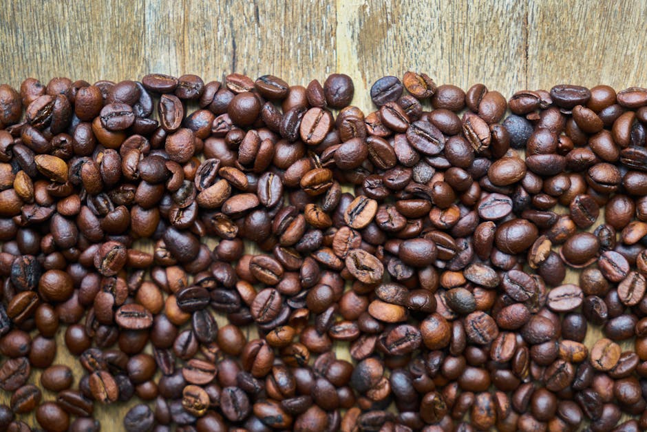 High-quality close-up shot of aromatic roasted coffee beans spread on a wooden table.